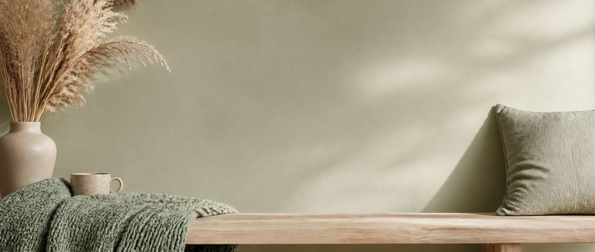 Knitted sage throw on a wooden bench by a sage wall